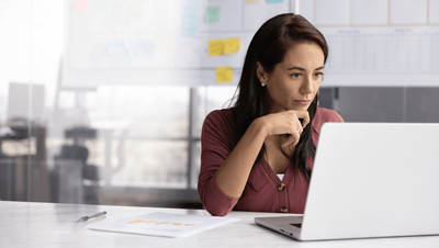 Business analyst at a desk using a laptop, studying the risks of full AI reliance in process analysis, modelling and simulation.